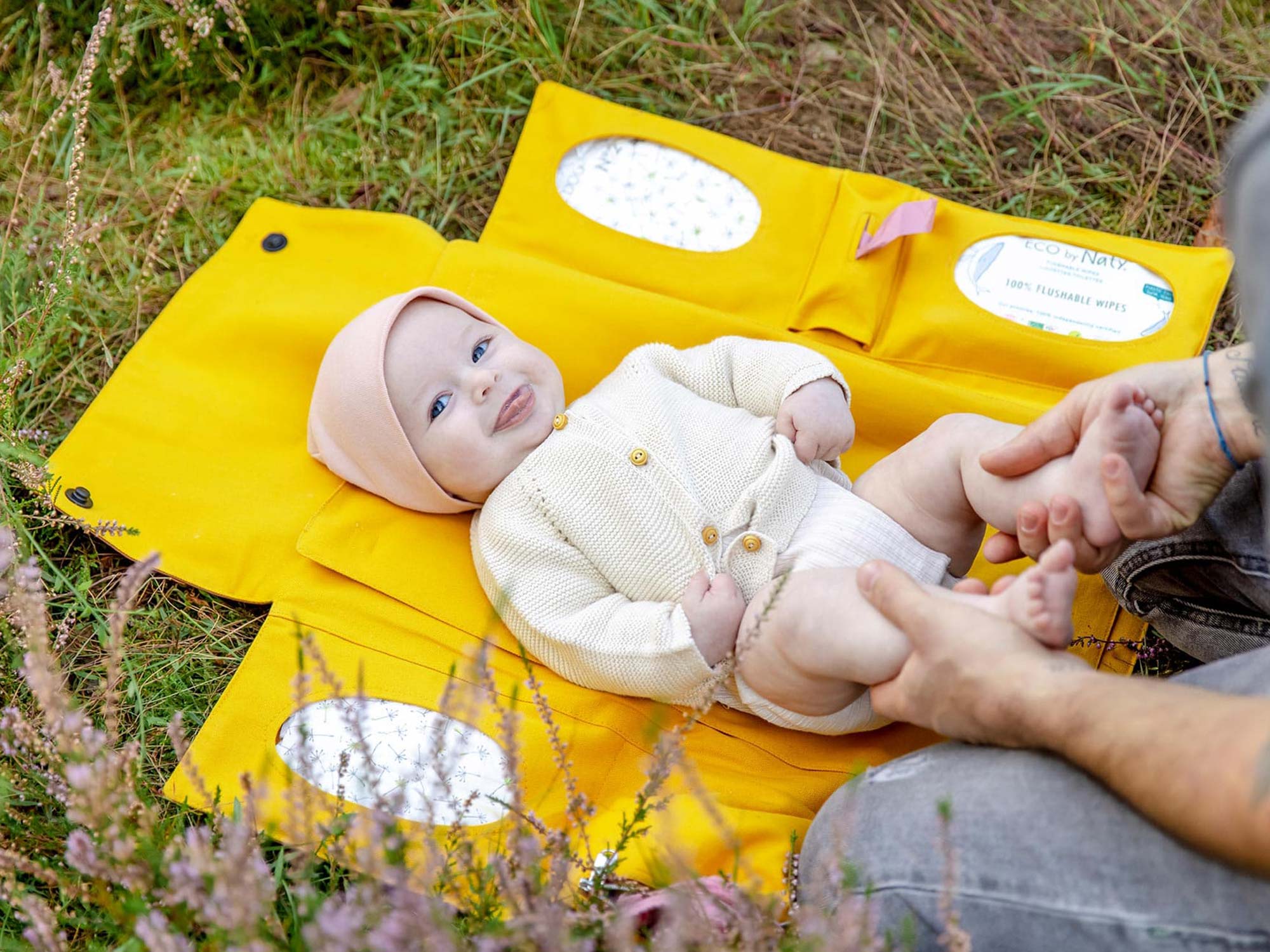 Baby wird auf einer faltbaren Wickelunterlage auf der Wiese bequem gewickelt